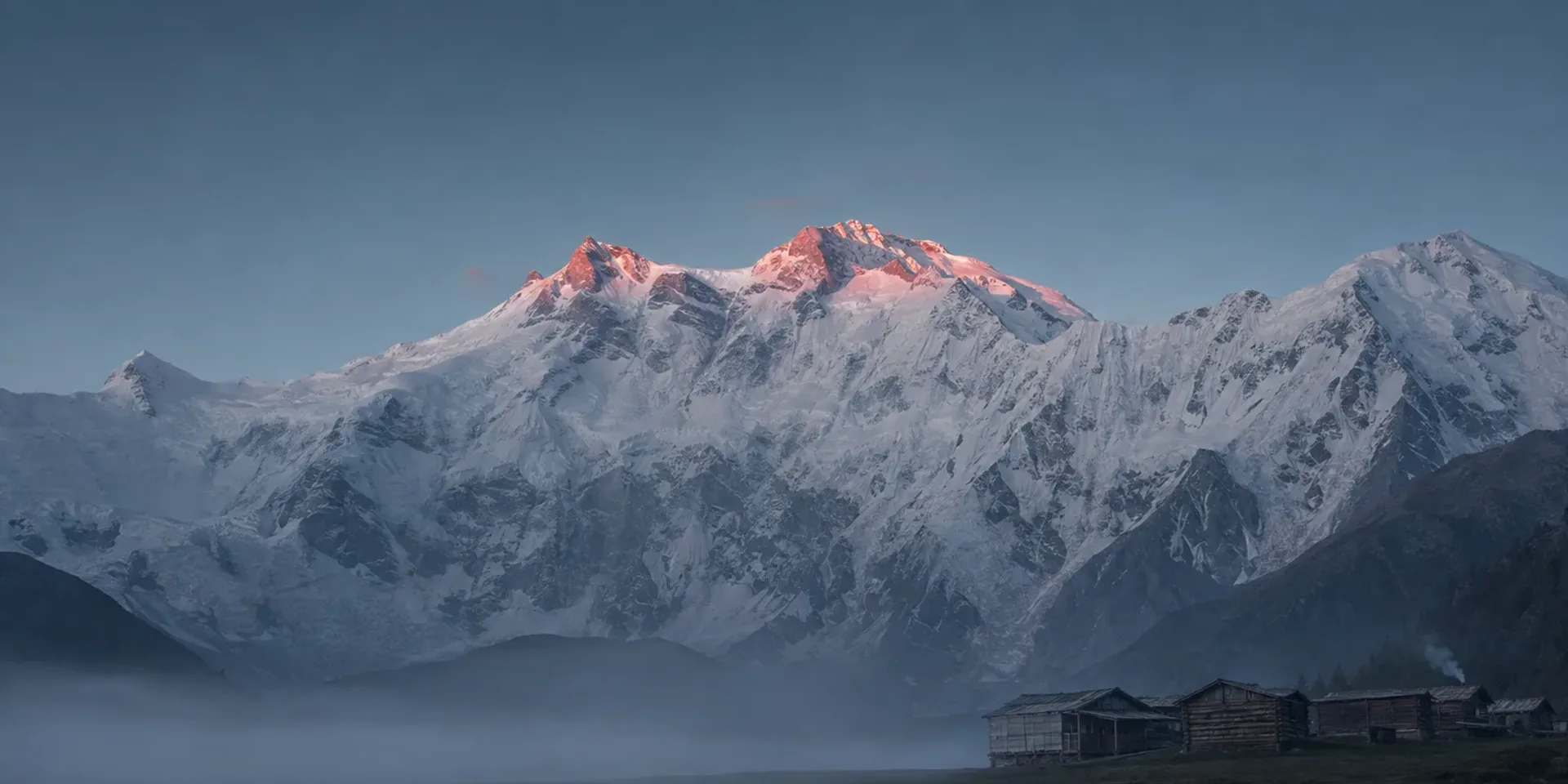 Fairy Meadows at first light, wooden huts on the grass beneath the Raikot face of Nanga Parbat.