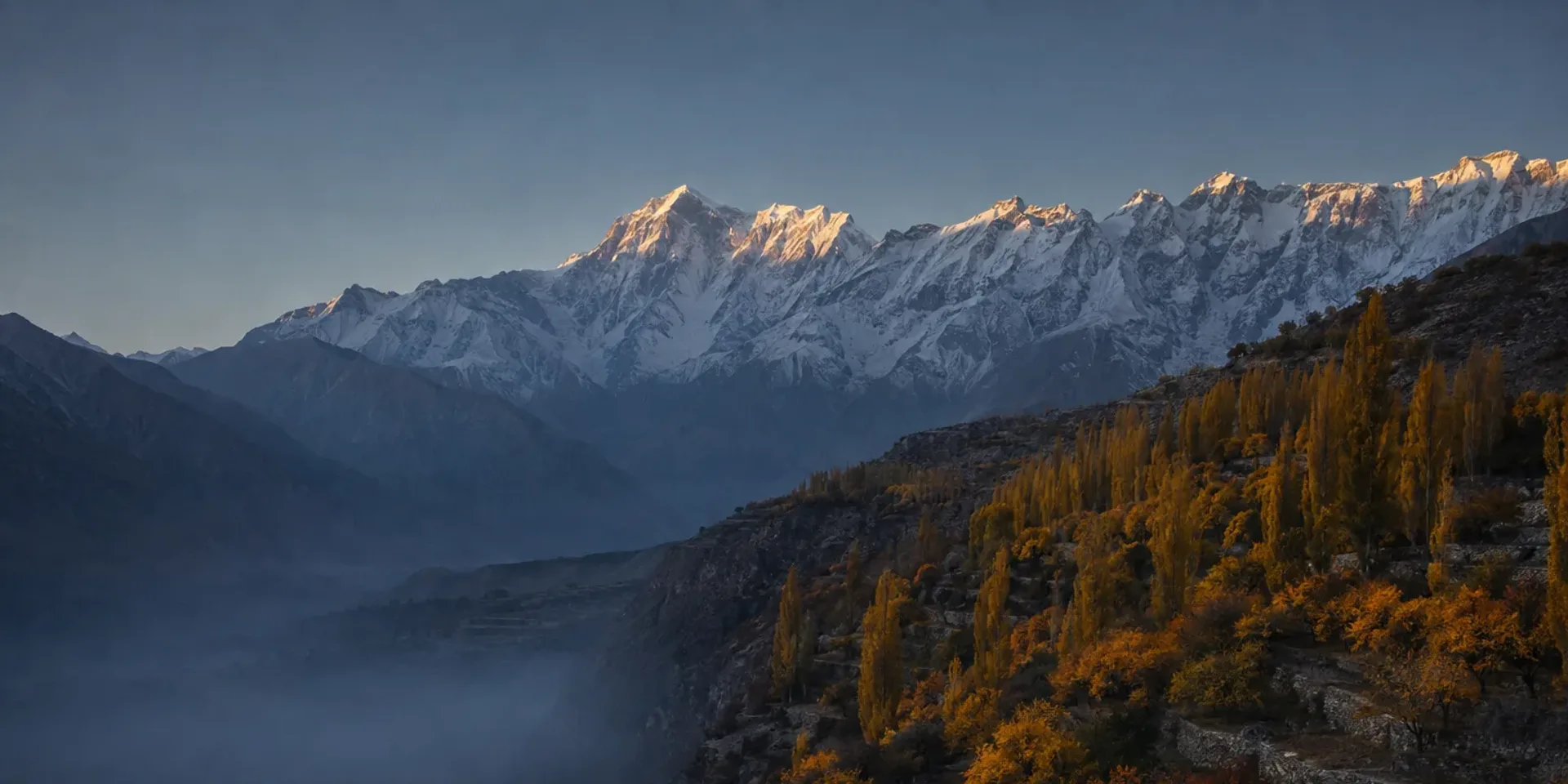 The Hunza valley from Duikar at sunrise in autumn, the lit snow wall of the Karakoram above the golden valley.