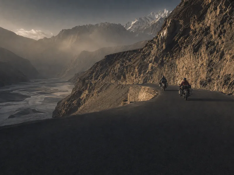 A dust-covered adventure motorcycle with aluminium panniers parked at a viewpoint on the Karakoram Highway.