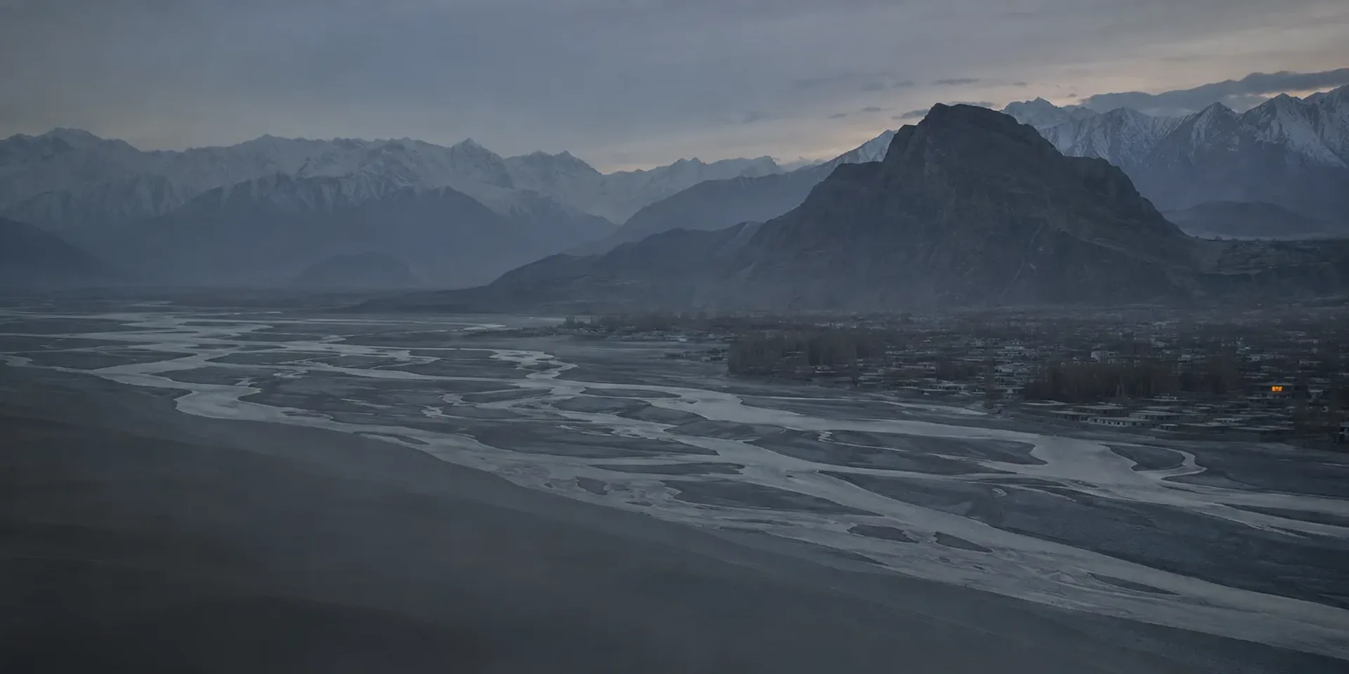 The Skardu valley at dusk, the braided Indus threading the flat valley floor below the Karakoram skyline.