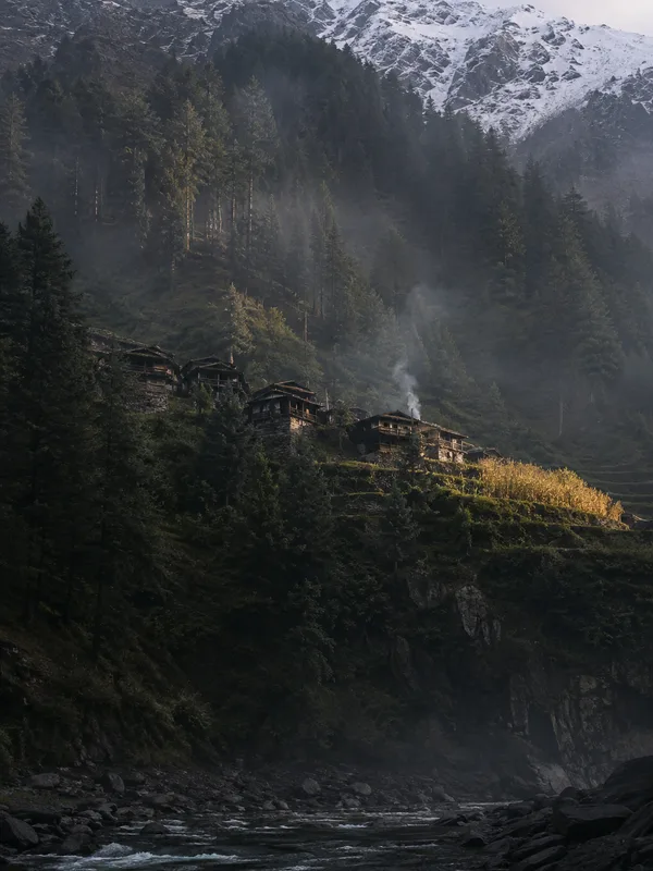 A steep forested valley side in upper Swat, deodar climbing from a fast river to snow-streaked rock above.